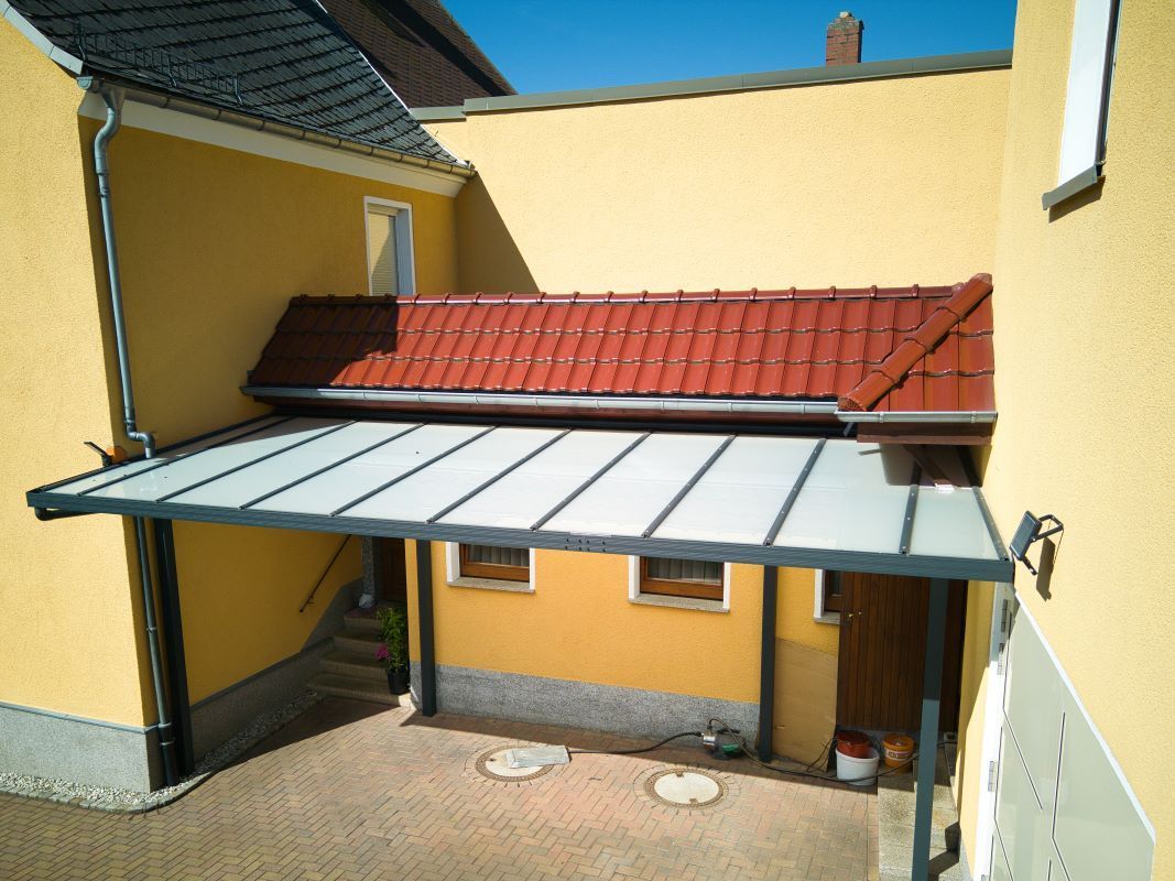 Ein gelbes Gebäude mit einem roten Ziegeldach und einem Baldachin darüber