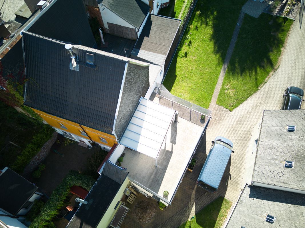 Eine Luftaufnahme eines Hauses, vor dem ein blauer Lieferwagen geparkt ist.