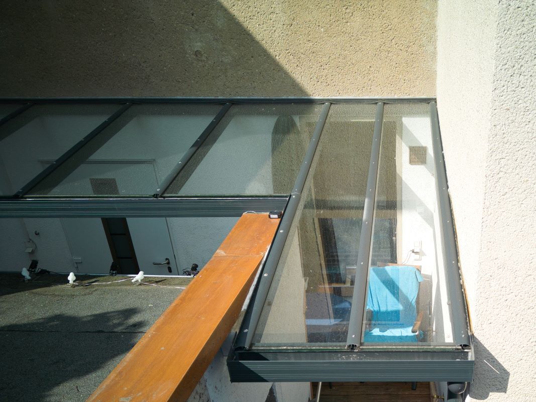 Ein Balkon mit Glasdach und Holzgeländer