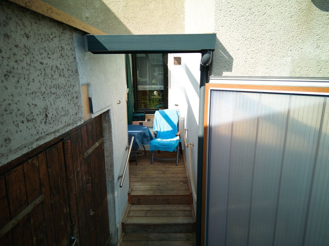 Ein blauer Stuhl steht auf einem Holzdeck neben einem Garagentor.