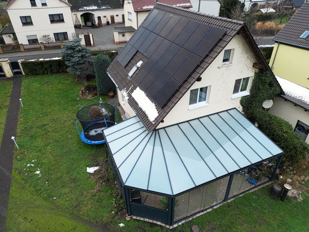 Eine Luftaufnahme eines Hauses mit Solarmodulen auf dem Dach.
