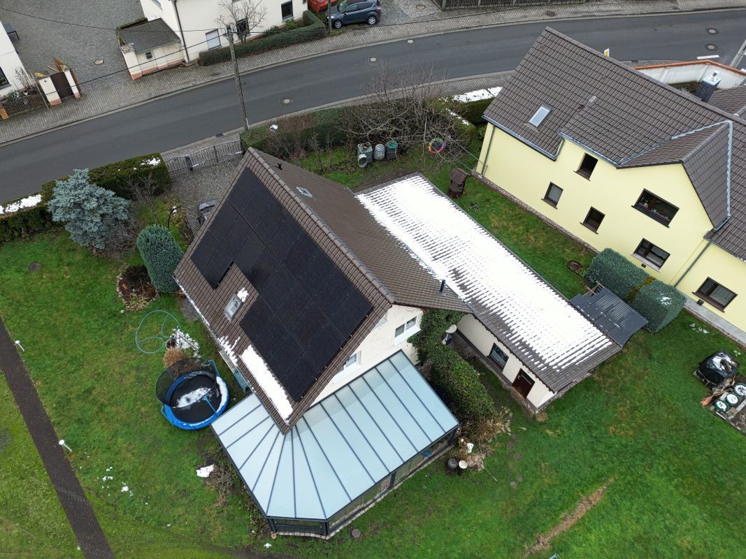 Eine Luftaufnahme eines Hauses mit Solarmodulen auf dem Dach.