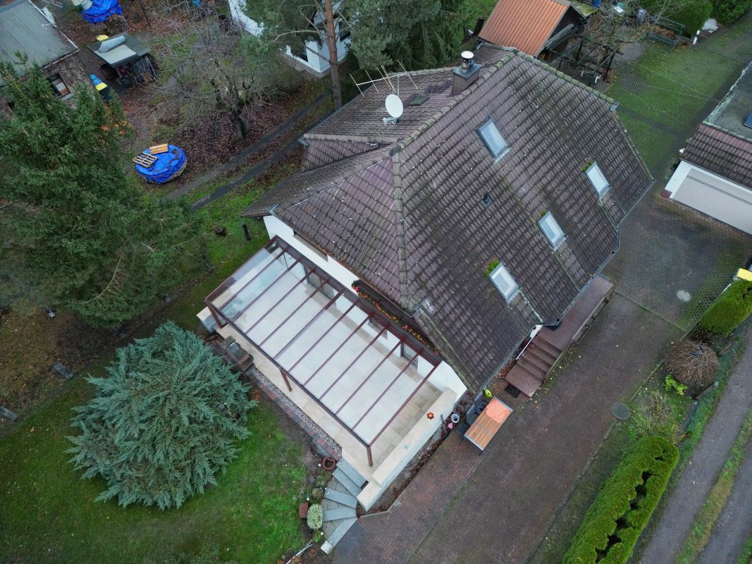 Eine Luftaufnahme eines Hauses mit einem Glasdach, umgeben von Bäumen.