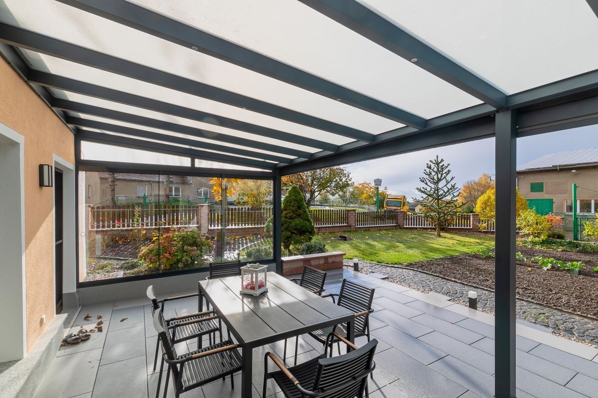 Eine Terrasse mit Tisch und Stühlen unter einem Baldachin.