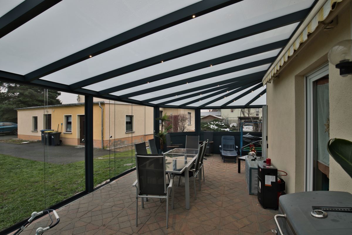 Eine Terrasse mit Tisch und Stühlen unter einem Baldachin