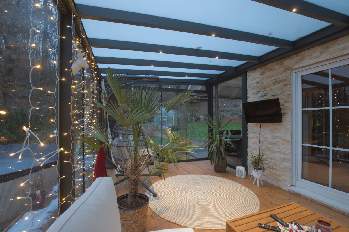 Ein Wohnzimmer mit vielen Fenstern und einem Fernseher an der Wand