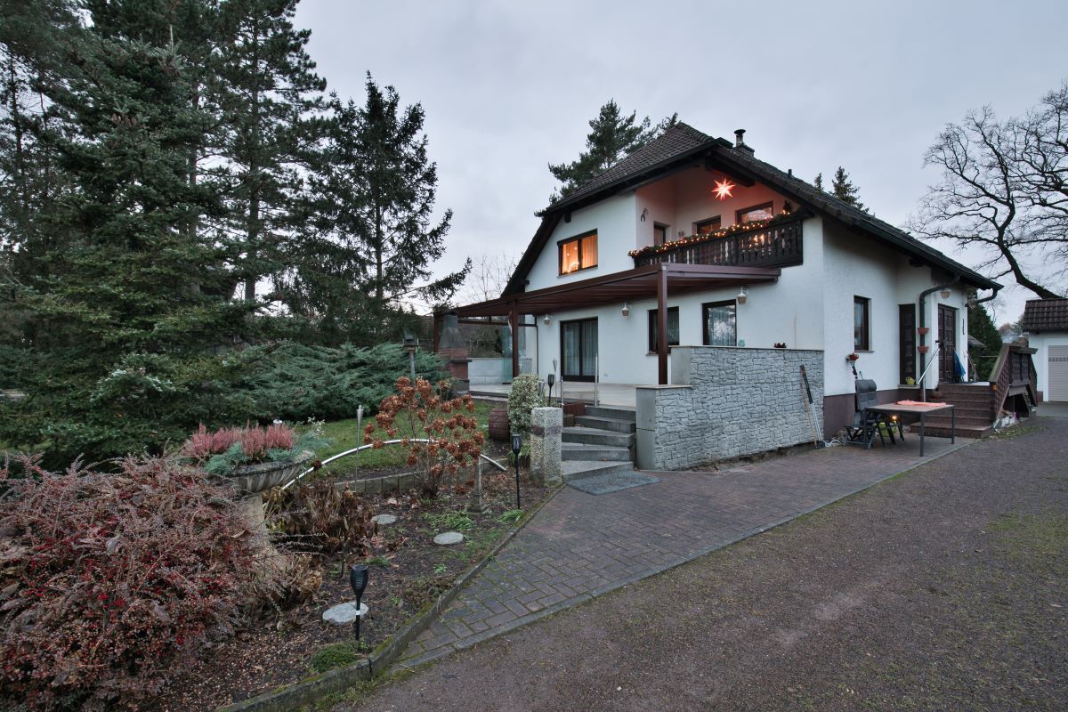 Ein großes weißes Haus mit Balkon ist von Bäumen umgeben