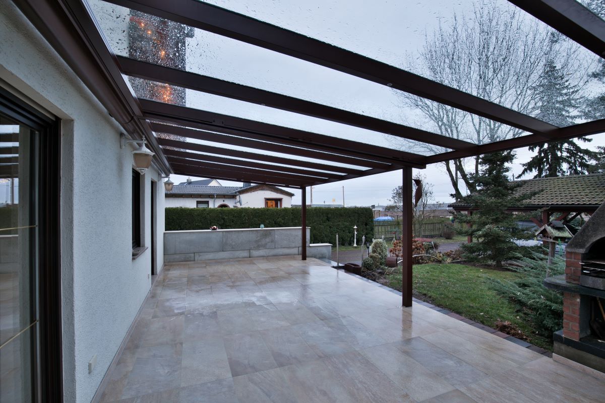 Eine leere Terrasse mit einem klaren Dach und einem Grill