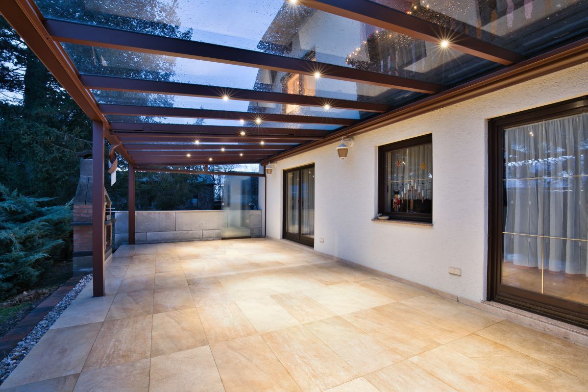 Eine große Terrasse mit Glasdach und Glasschiebetüren.