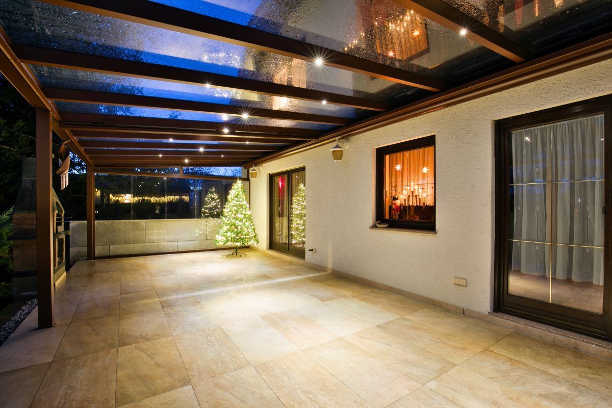 Eine große Terrasse mit Glasdach und einem Weihnachtsbaum im Hintergrund.