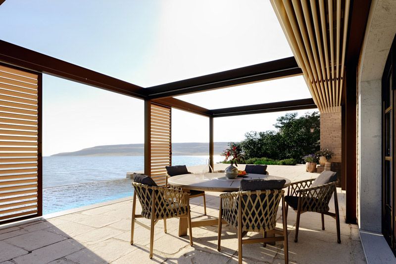 Eine Terrasse mit Tisch und Stühlen mit Blick auf das Meer.