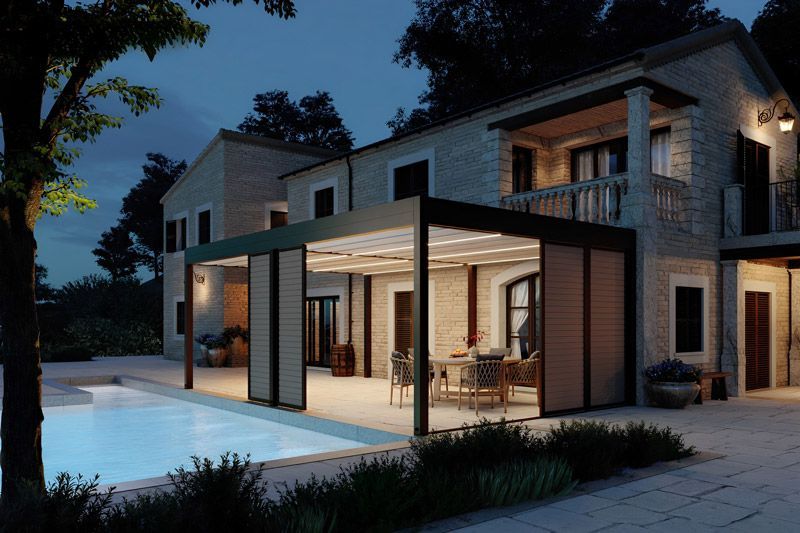 Ein Haus mit Swimmingpool und Pergola bei Nacht.