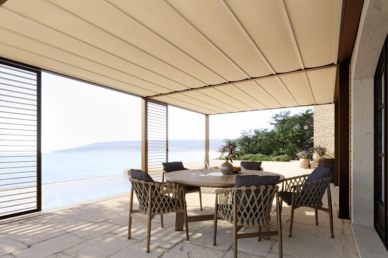 Eine Terrasse mit Tisch und Stühlen unter einem Baldachin mit Blick auf den Ozean.