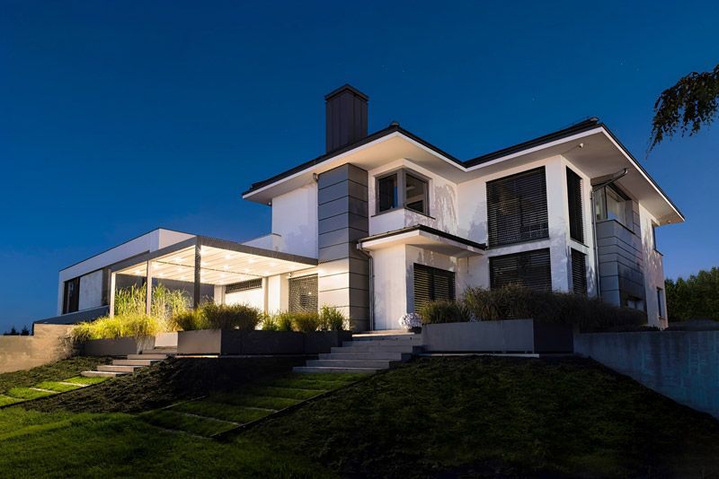 Ein großes weißes Haus mit vielen Fenstern ist nachts beleuchtet.