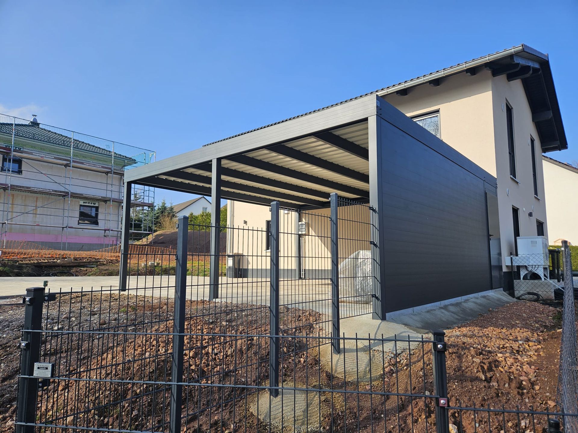 Vor einem Haus wird ein Carport gebaut.