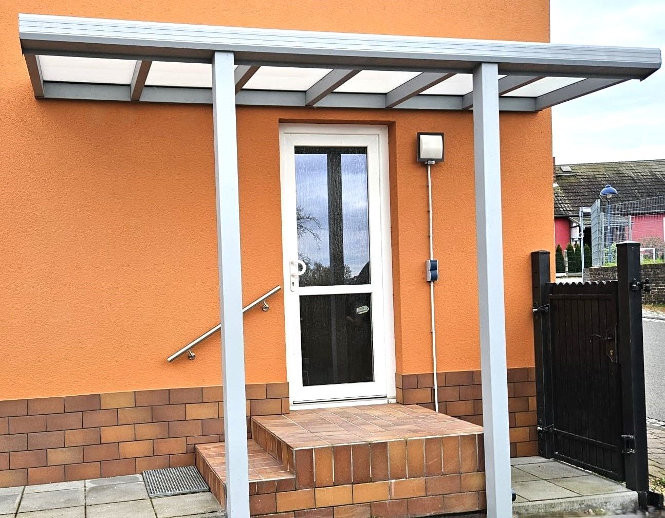 Ein orangefarbenes Gebäude mit einer weißen Tür und einem Vordach darüber