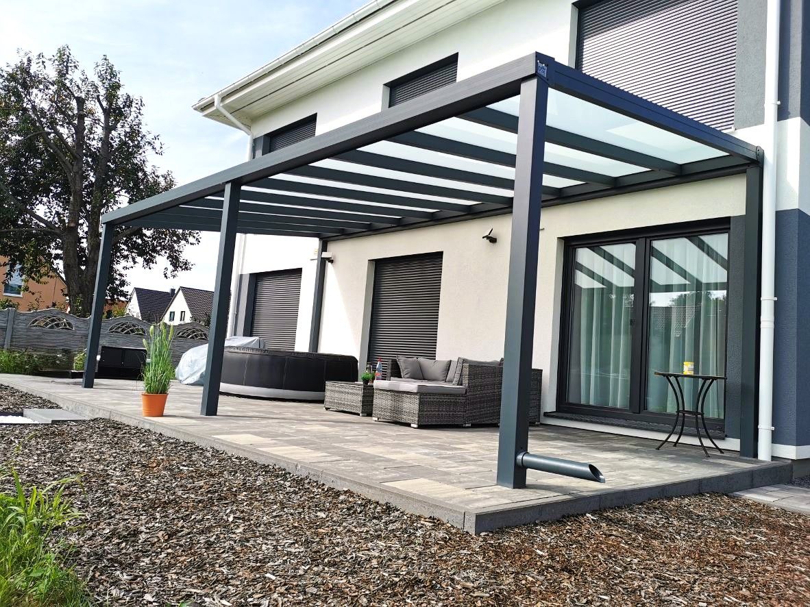 Ein Haus mit einer Glaspergola auf der hinteren Terrasse.