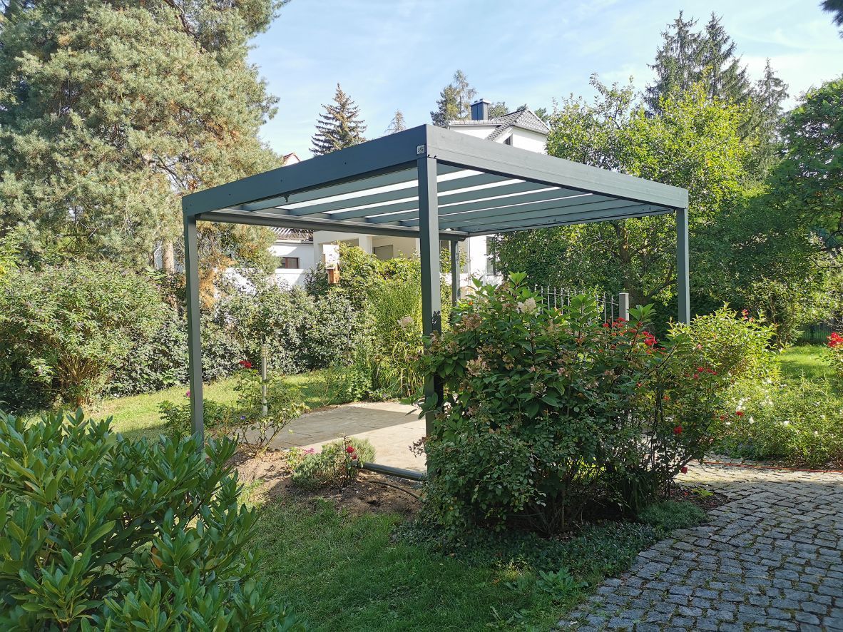 Eine Pergola steht inmitten eines von Bäumen umgebenen Gartens.