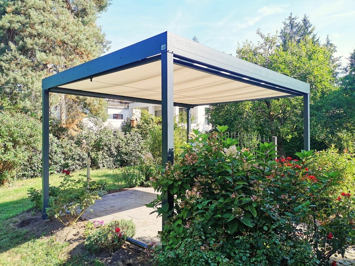 Eine Pergola steht mitten in einem Garten neben einem Busch.