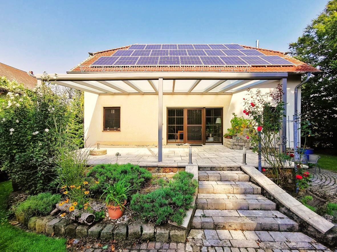 Ein Haus mit Solarzellen auf dem Dach und einer Treppe, die dorthin führt.