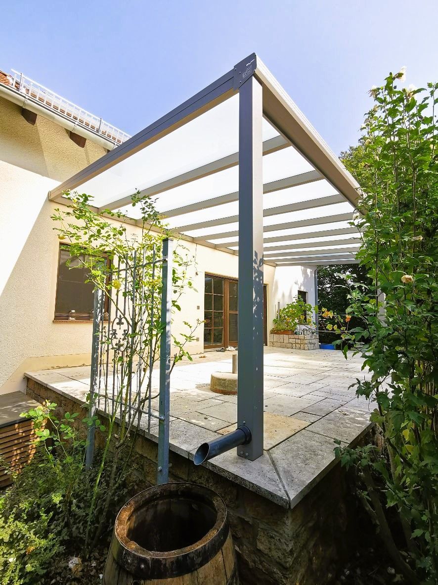 Eine Terrasse mit Pergola und Brunnen vor einem Haus.