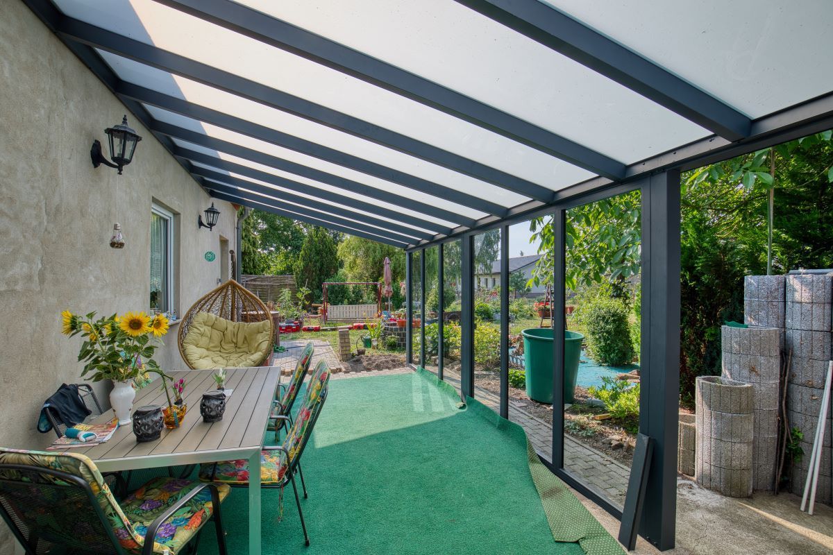 Eine Terrasse mit Tisch und Stühlen unter einem Baldachin.