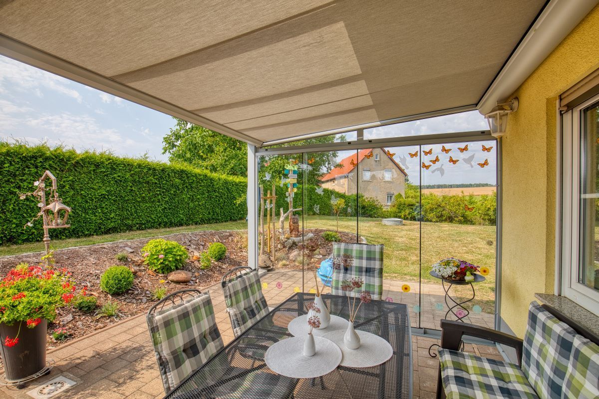 Eine Terrasse mit Tisch und Stühlen unter einem Baldachin.