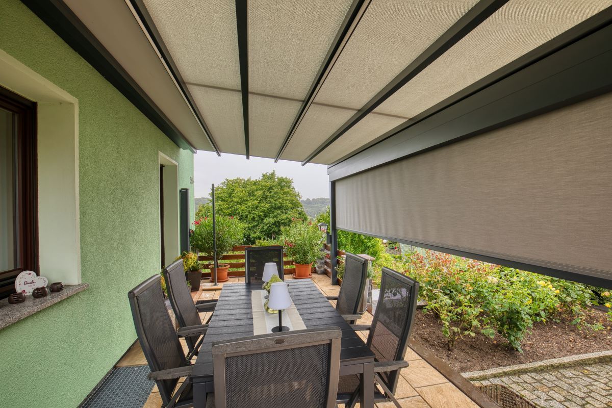 Eine Terrasse mit Tisch und Stühlen unter einem Baldachin