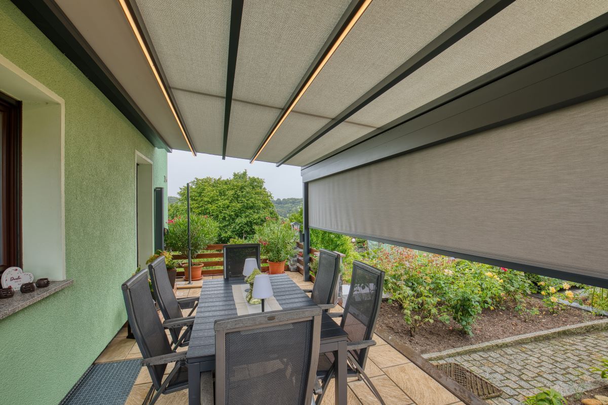 Eine Terrasse mit Tisch und Stühlen unter einem Baldachin