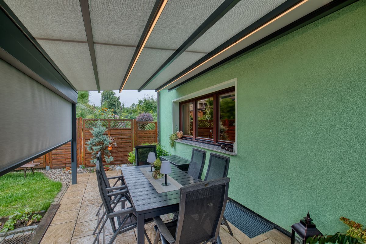 Eine Terrasse mit Tisch und Stühlen unter einem Baldachin.