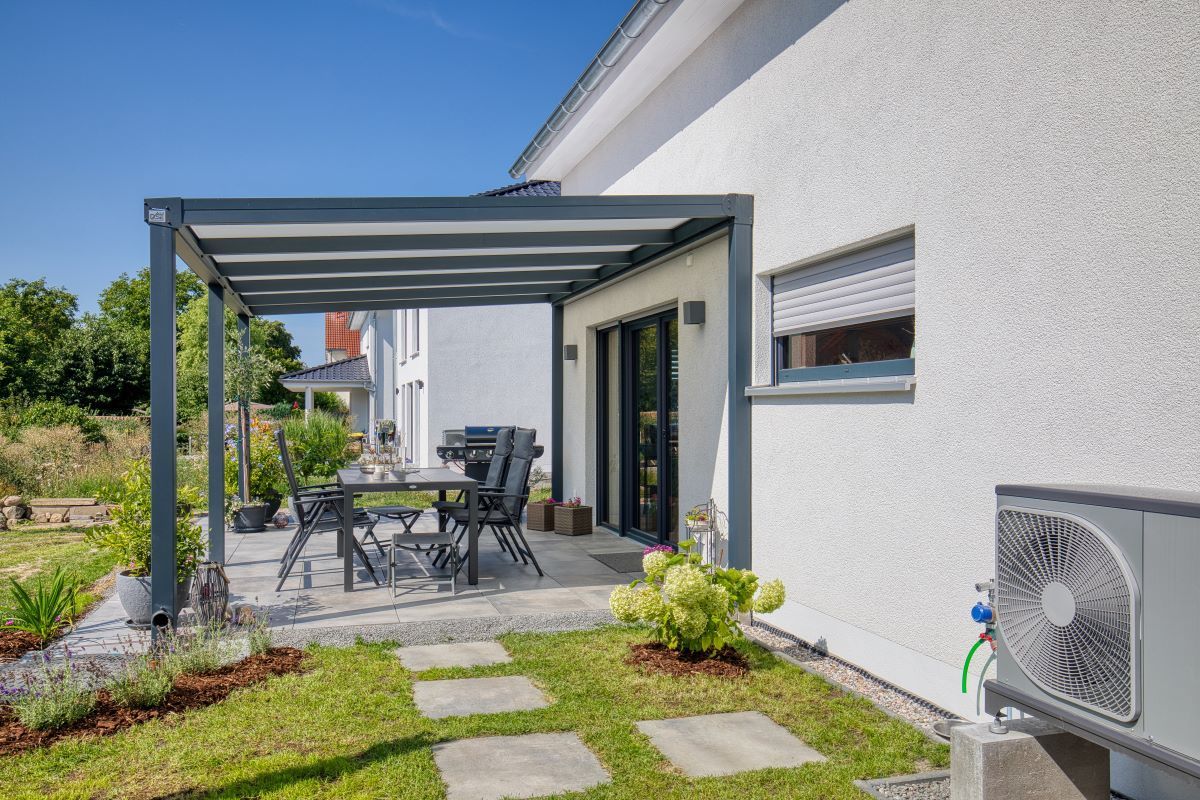 Ein Haus mit einer Pergola und einem Tisch und Stühlen im Hinterhof.