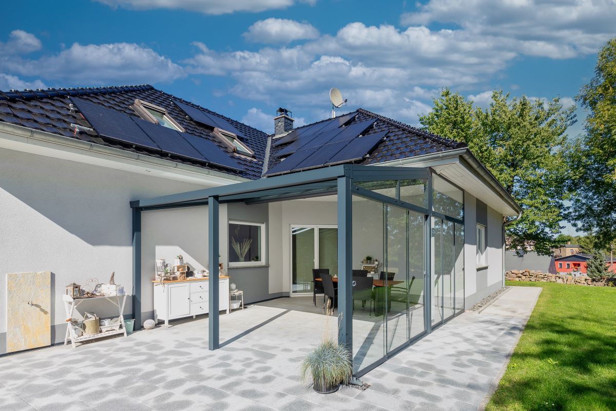 Ein Haus mit Terrasse und Sonnenkollektoren auf dem Dach.
