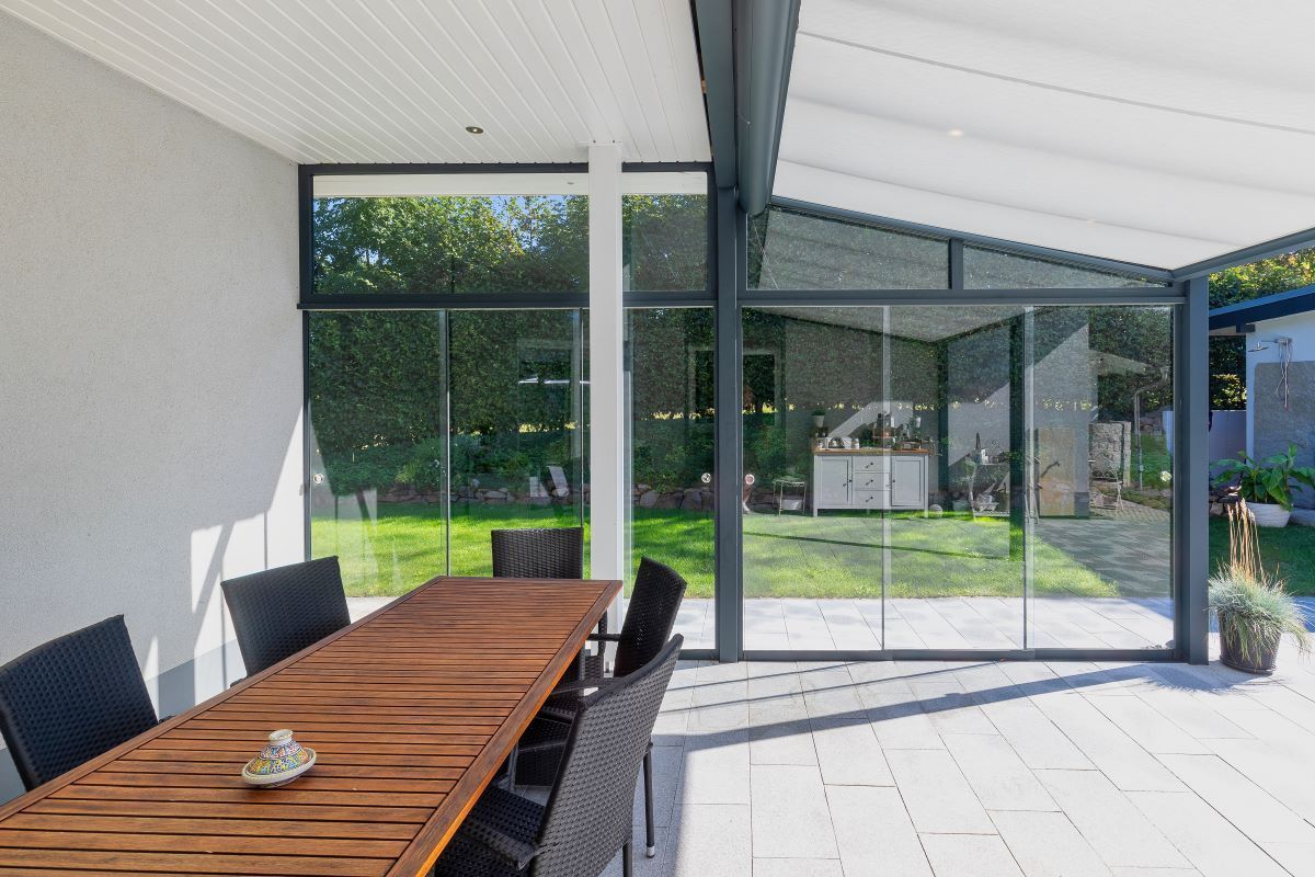 In dem Zimmer mit vielen Fenstern gibt es einen Tisch und Stühle.