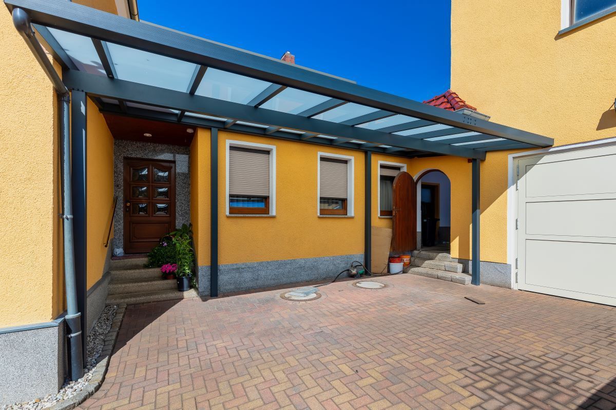 Ein gelbes Haus mit einem Carport davor