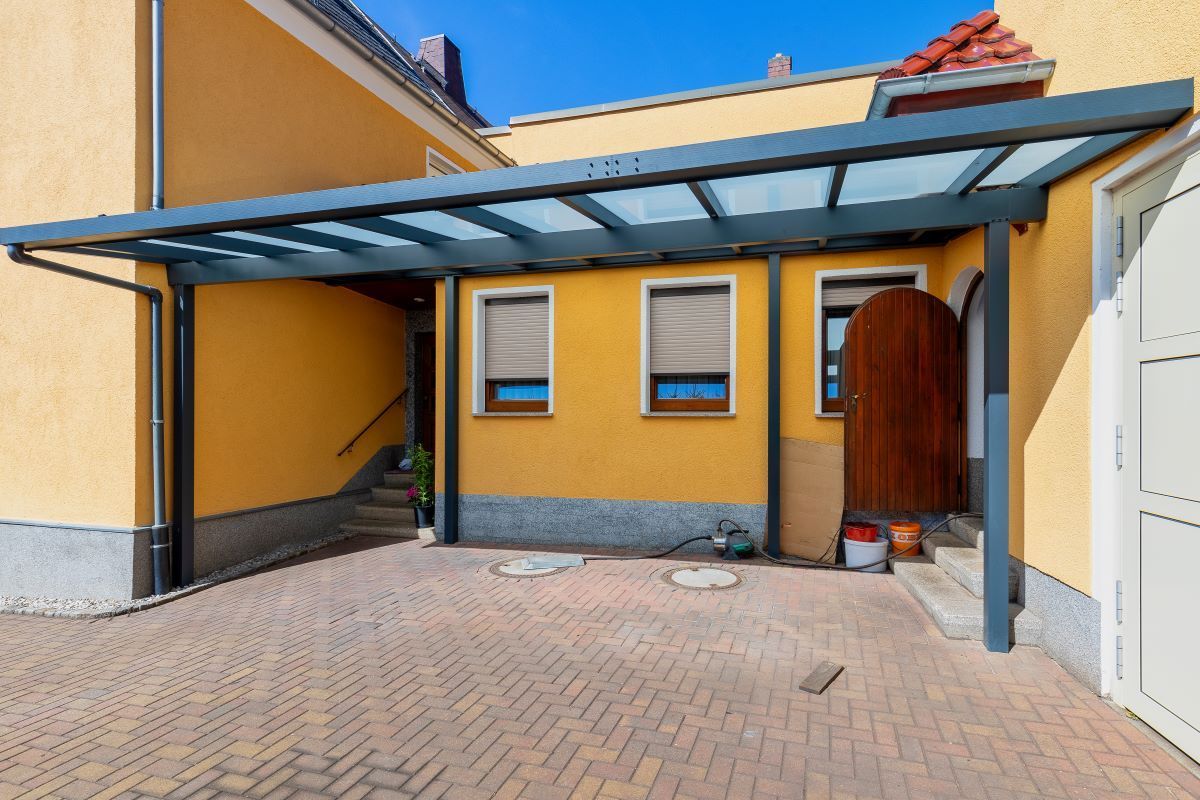 Ein gelbes Haus mit einem Carport davor