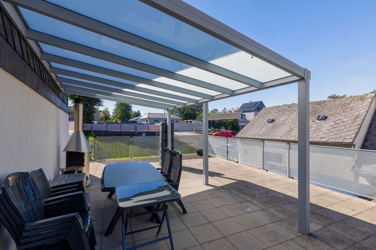 Eine Terrasse mit Tisch und Stühlen unter einem Baldachin.