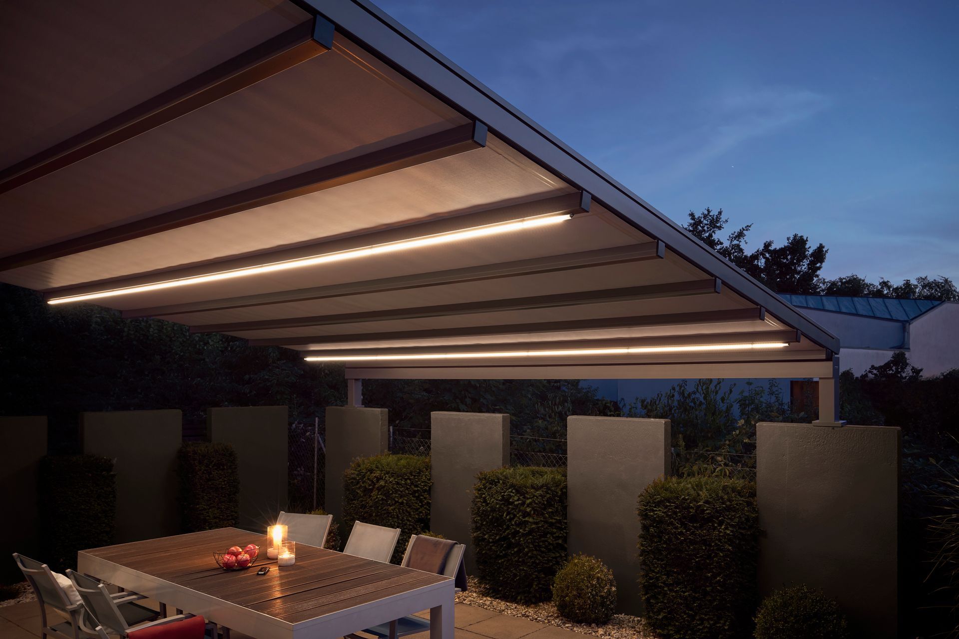 Eine Terrasse mit Tisch und Stühlen unter einer Markise bei Nacht