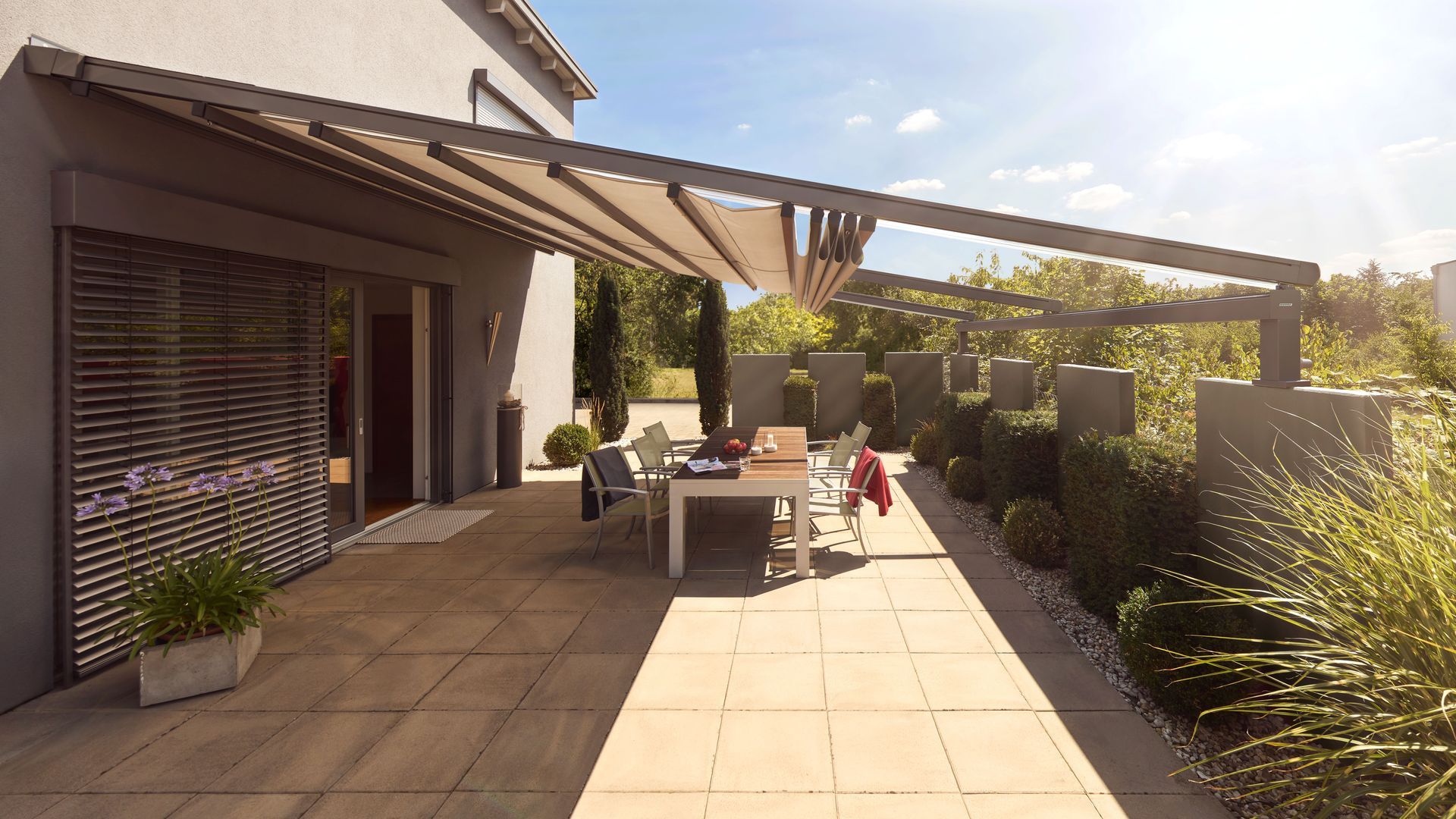 Eine Terrasse mit Tisch und Stühlen unter einem Baldachin.