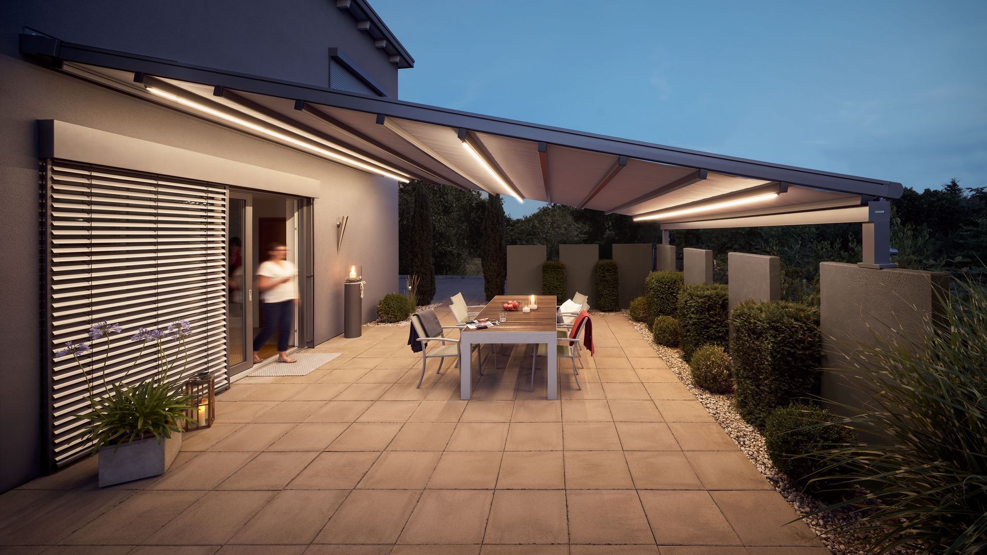 Eine Terrasse mit Tisch und Stühlen unter einem Baldachin bei Nacht.