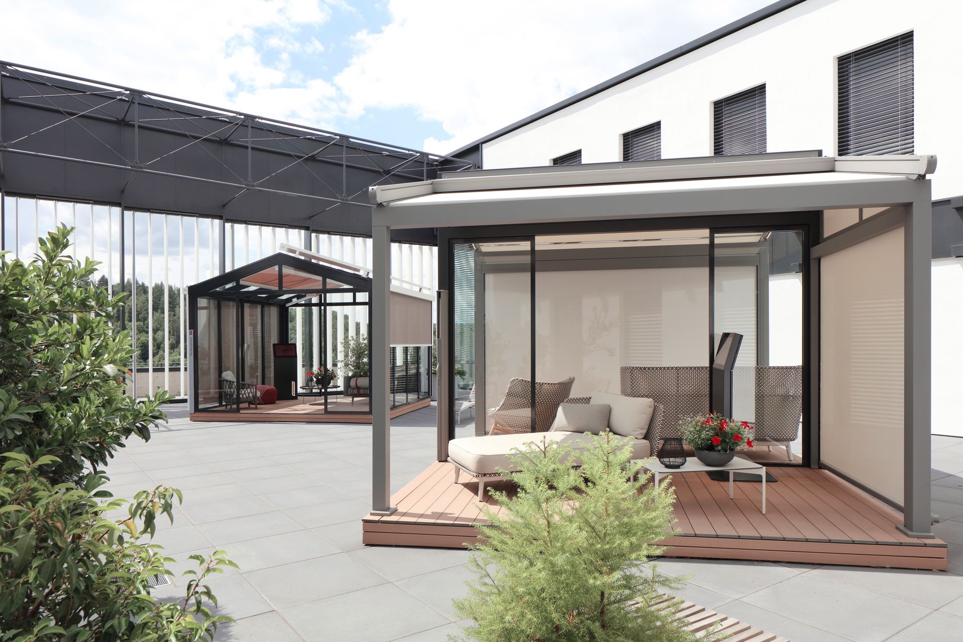 Eine Terrasse mit Pergola und Couch vor einem Gebäude.