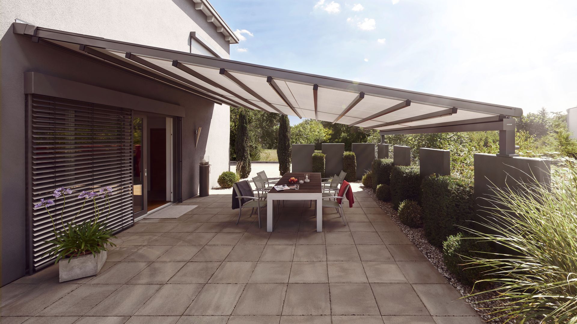 Eine Terrasse mit Tisch und Stühlen unter einem Baldachin.