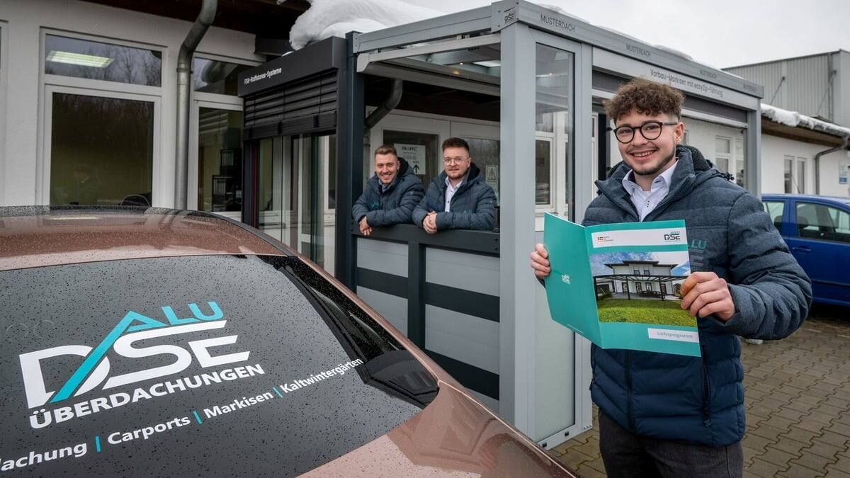 Ein Mann hält einen Ordner vor einem Auto.
