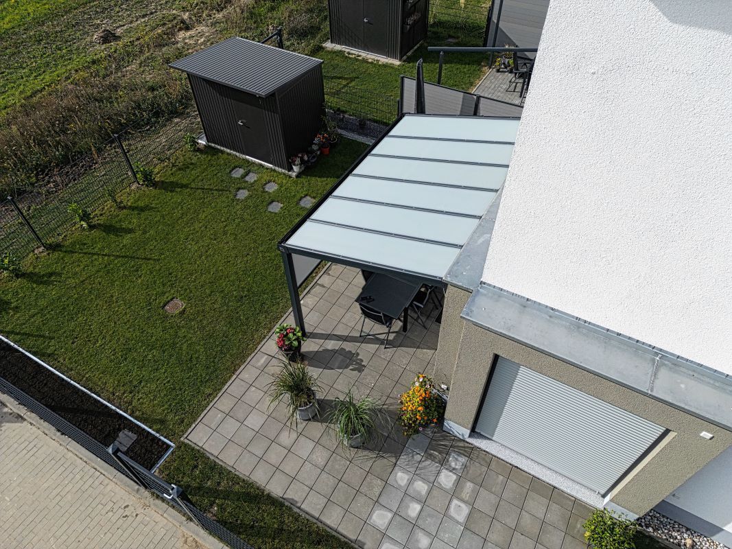 Eine Luftaufnahme eines Hauses mit einer Terrasse und einer Pergola.