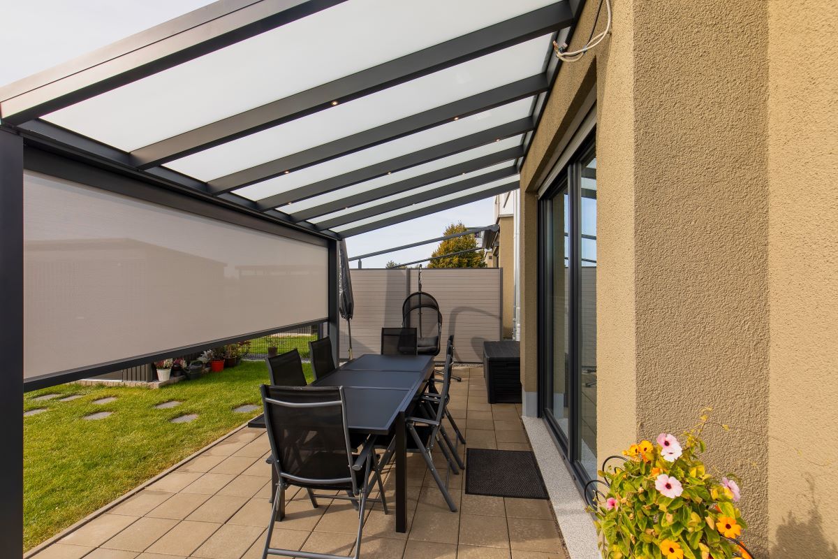 Eine Terrasse mit Tisch und Stühlen unter einem Baldachin.