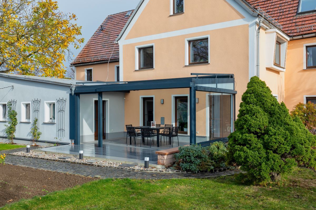 Ein großes Haus mit einer Terrasse und einem Tisch und Stühlen davor.