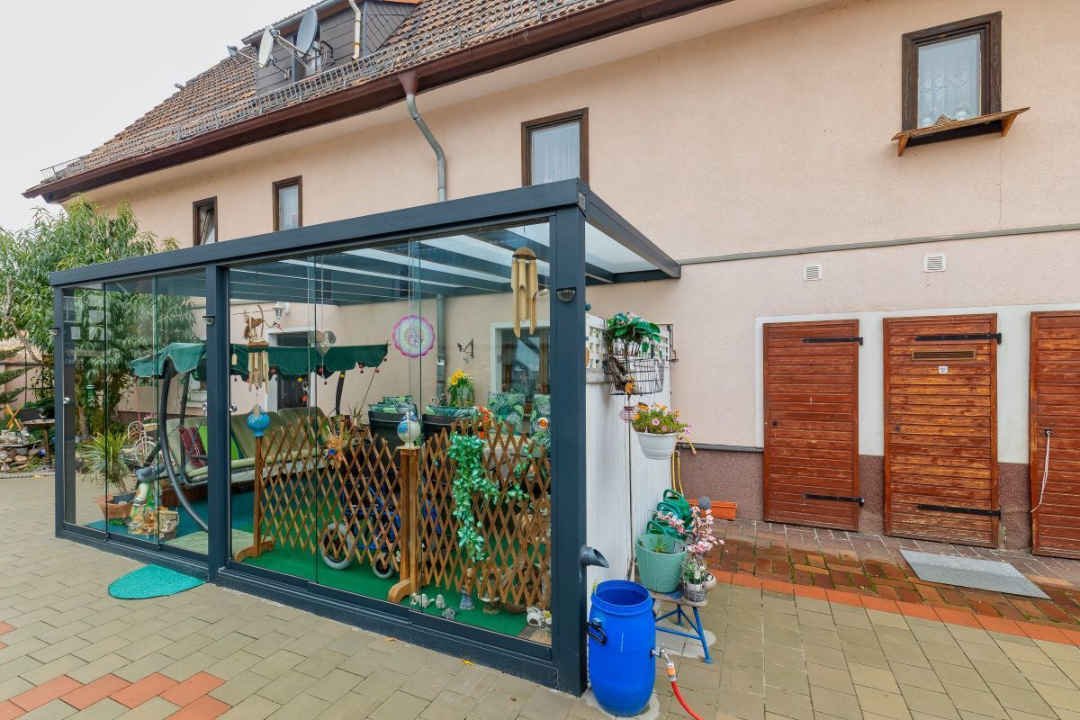 Vor einem Haus steht eine Pergola.
