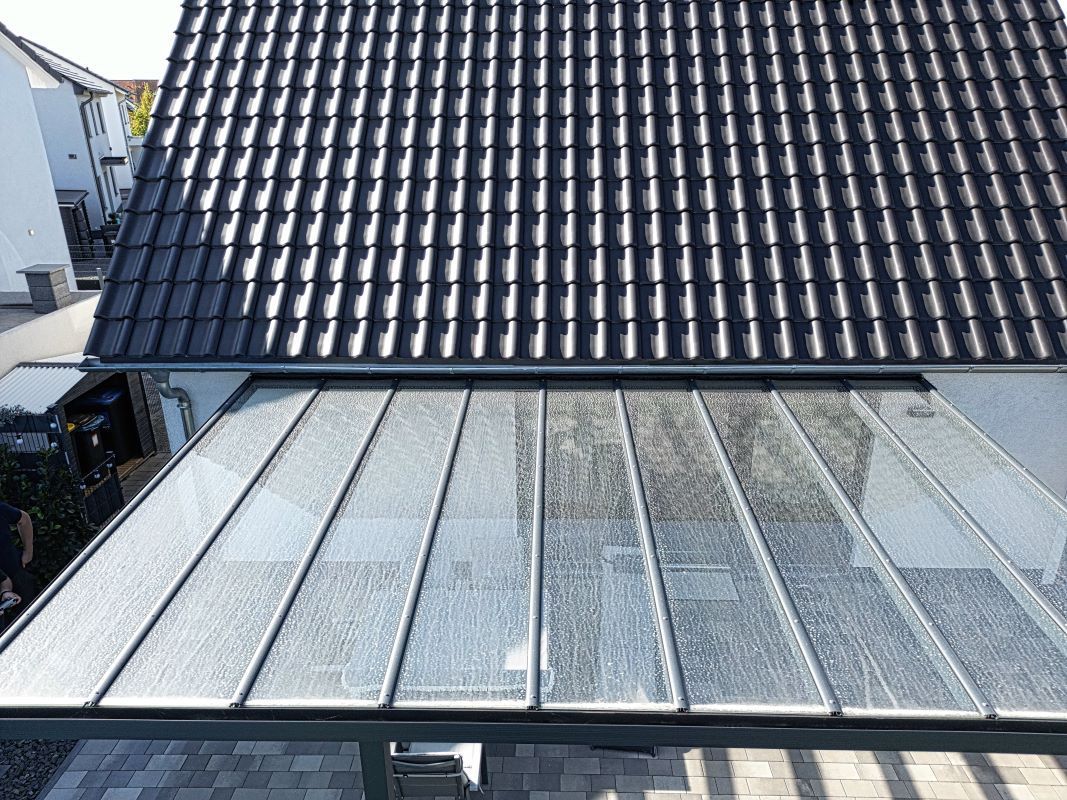 Das Dach eines Hauses mit einem Glasdach und einem schwarzen Ziegeldach.