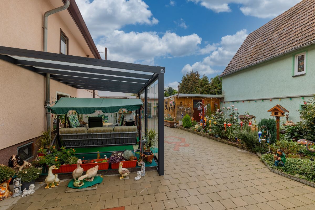 Eine Terrasse mit Schaukel und Enten vor einem Haus.