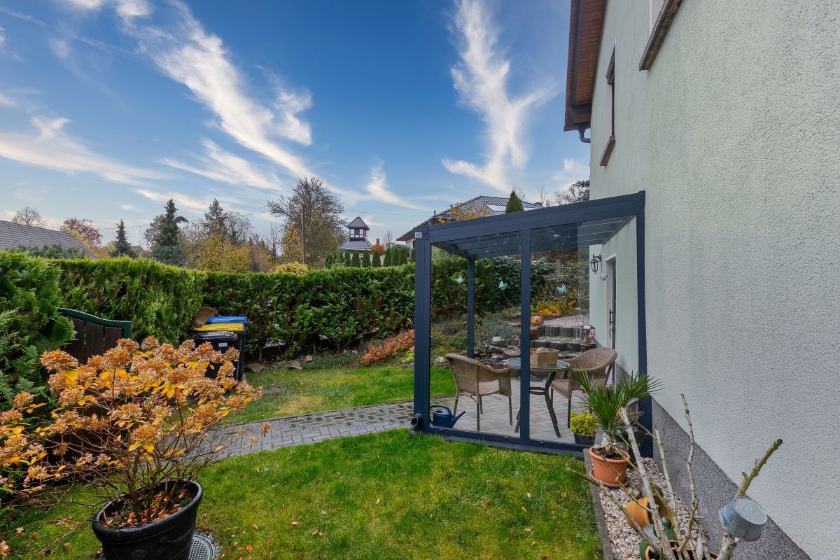 Im Hinterhof eines Hauses gibt es eine Terrasse mit Tisch und Stühlen.