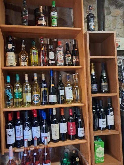 Estanterías de madera repletas de botellas de licor y vino variadas en un bar o restaurante.